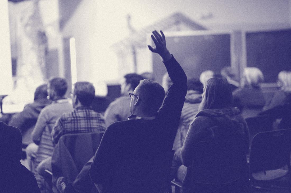 A camper raising a hand to ask a question during a session
