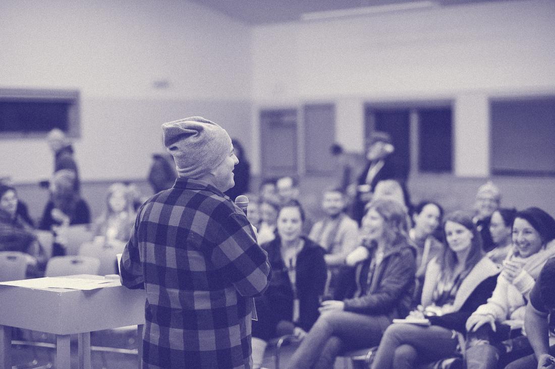 A camper in buffalo plaid leading a session while the room laughs